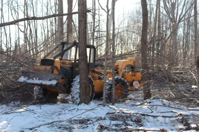 Heavy machinery clearing debris and vegetation in a wooded area, showcasing professional lot clearing services by Woods Forestry Solutions.